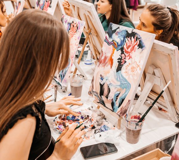 Friends painting colourful floral canvases at a paint and sip class