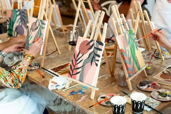 Hens painting leafy canvases on easels at a paint and sip class