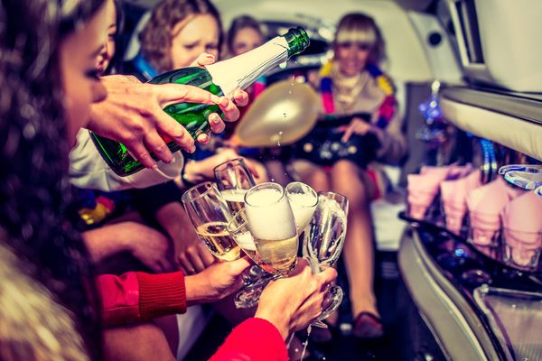 A gorgeous hen pours champagne into glasses on a limousine cruise