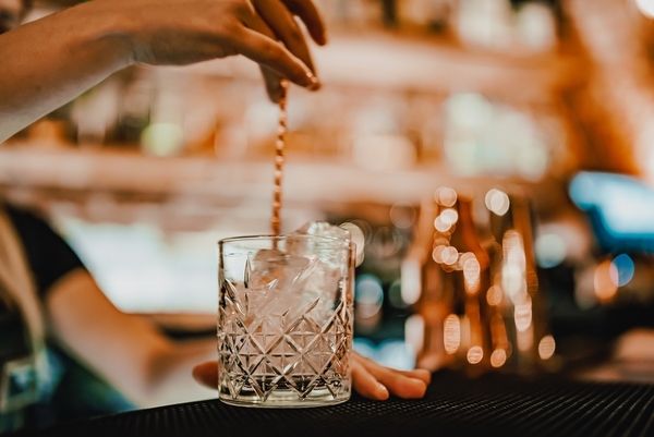 A bartender stirring a drink over ice in a crystal glass