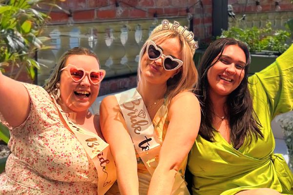 Bride in a Bride to Be sash and heart sunglasses with two friends on a Melbourne rooftop