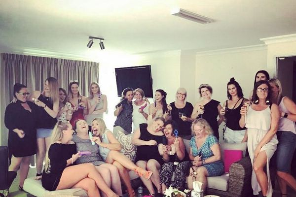 Large group of women laughing together on couches in a lounge room party