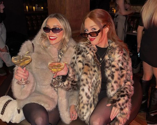 Two friends in faux fur and leopard print with sunglasses and coupe cocktails