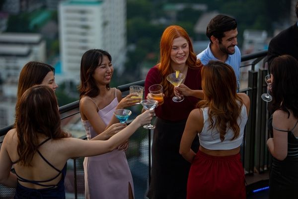 small group of women gathered together on a rooftop bar clinking together glasses of bubbly