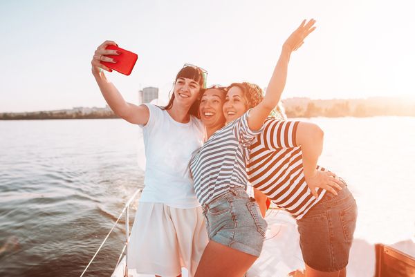 A lovely hen and her two closest friends smile and pose for a selfie photo in their private boat cruise