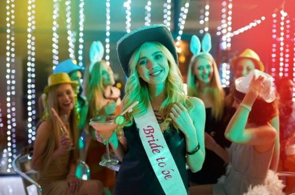 A hens party package with a group of women laughing with the bride to be at the front in a sash