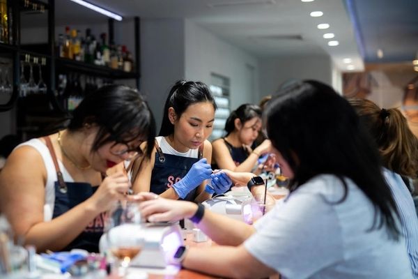 Guests having manicures at a beauty bar with a cocktail on the counter