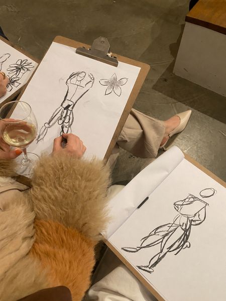 Two hens sketching figure drawings on clipboards at a life drawing class