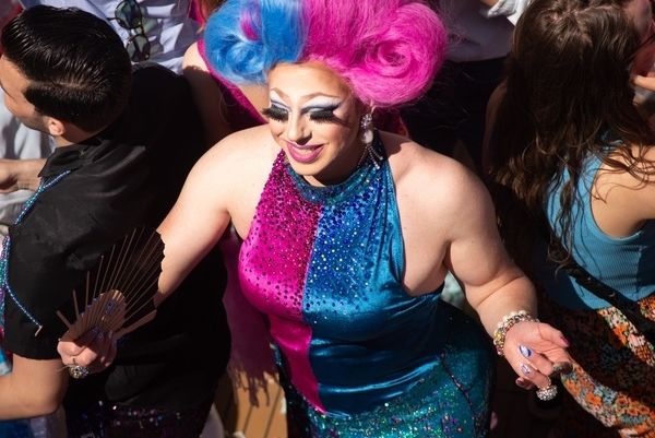 A drag queen in a colourful sequin outfit entertaining a group of guests