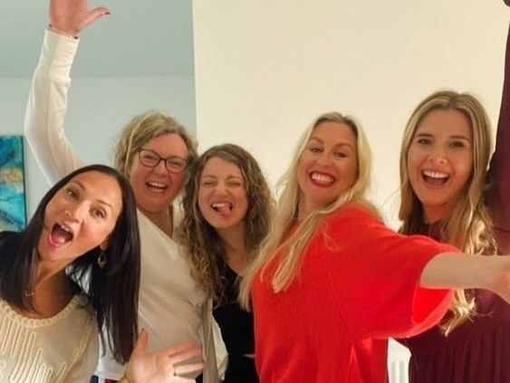 Five friends posing and laughing together at home