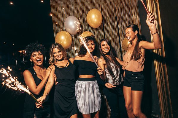 Five gorgeous ladies waving sparklers and balloons and celebrating their hen party hosted in a private venue