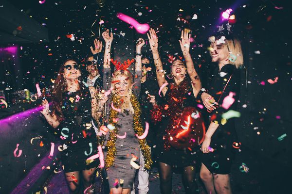 Gorgeous ladies enjoying themselves and dancing in a luxury VIP booth adorned with cascading feathers and confetti