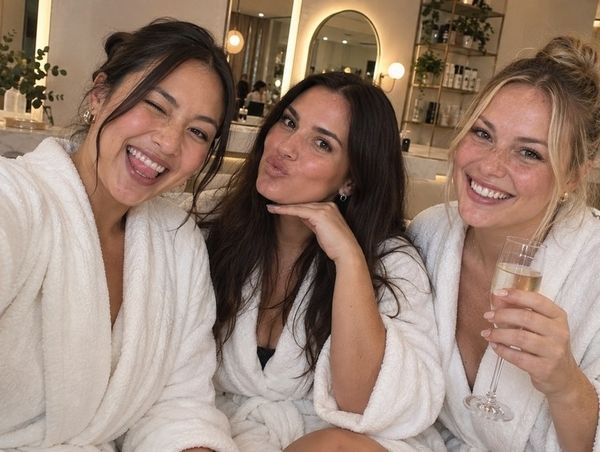 Three friends in white robes pulling faces for a selfie with bubbly at the day spa