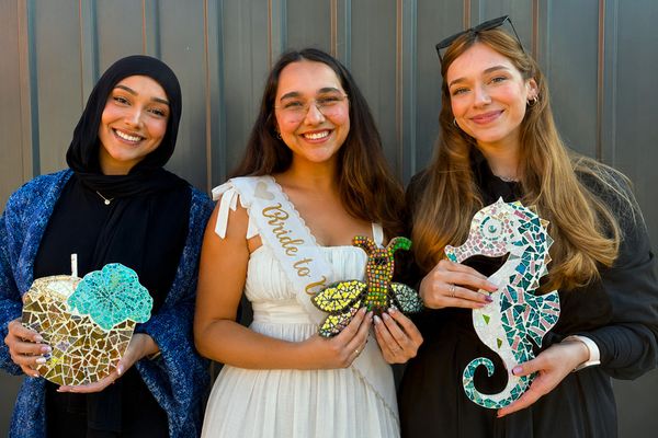 Bride to be in a sash with two friends, all holding the glass mosaics they made