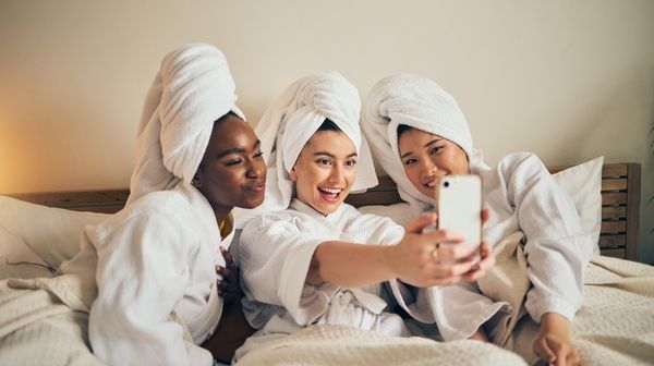 Three gorgeous ladies in white robes took a selfie photo at a day spa