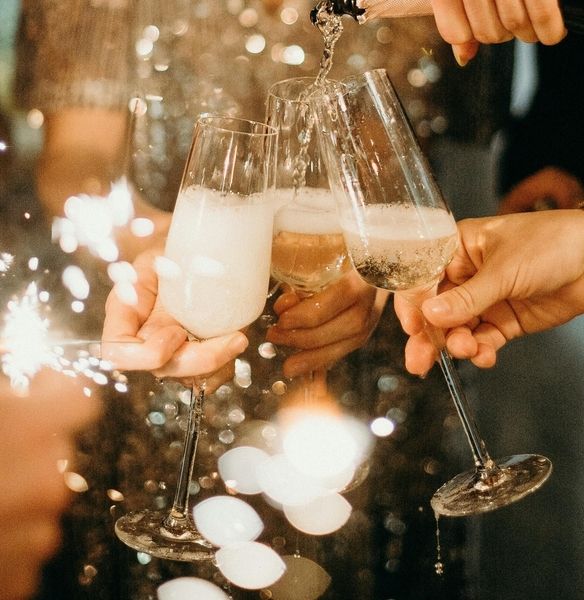 Ladies pour champagne into a glass and toast it with a sparkler on the side
