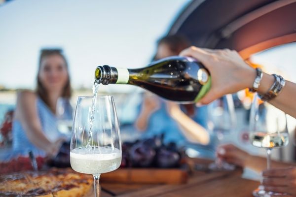 The lovely hen pours a champagne into glass in her private hens boat cruise