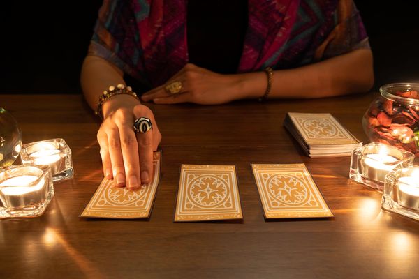 The tarot reader places the cards on a brown table and starts the tarot reading