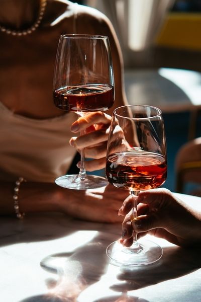 Two friends clinking glasses of rose wine