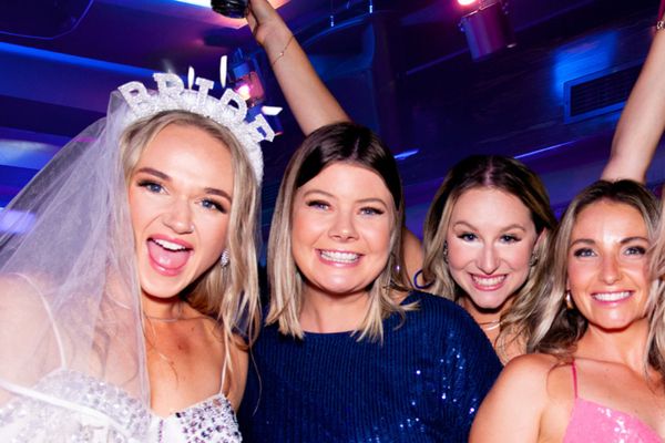 Bride in a veil and Bride headband laughing with friends in sequins