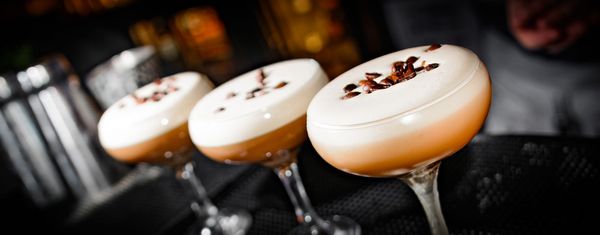three espresso marinits lined up on a bar with coffe beans sprinkled on top