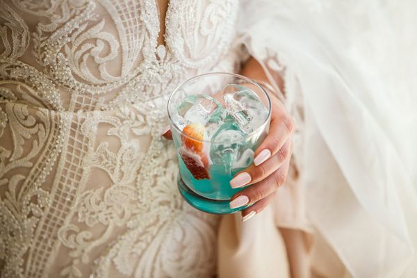bride to be holds a blue cocktail and is in wedding dress on her hens night