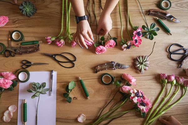 Setting up various floral arrangements and decorations on a simple brown table for flower crown making workshop