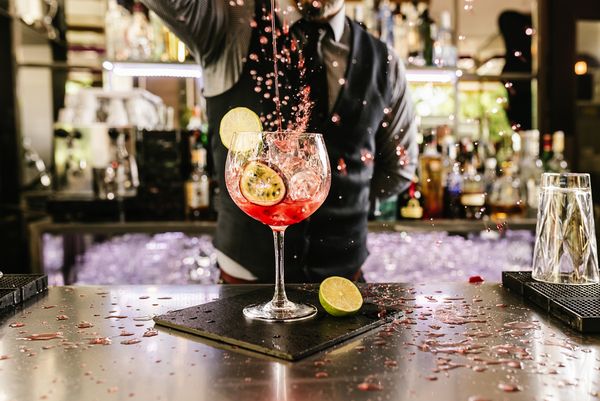 A bartender finishing a pink cocktail with lime as it splashes