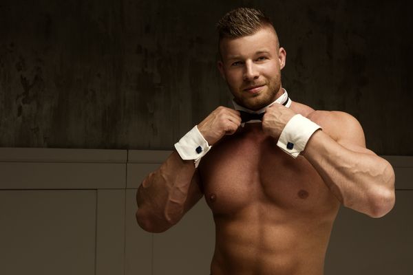 A shirtless waiter in a bow tie and cuffs