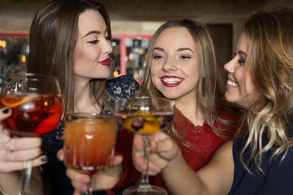 Three lovely ladies raise their favourite cocktail drinks and make a toast during the hen party