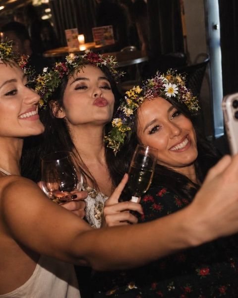 Three friends in flower crowns pouting for a selfie with drinks