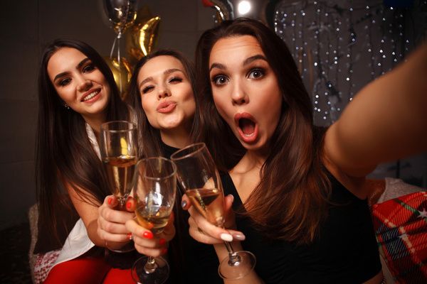 Hen strikes a silly pose and smiles for a picture with her best friends in a private room