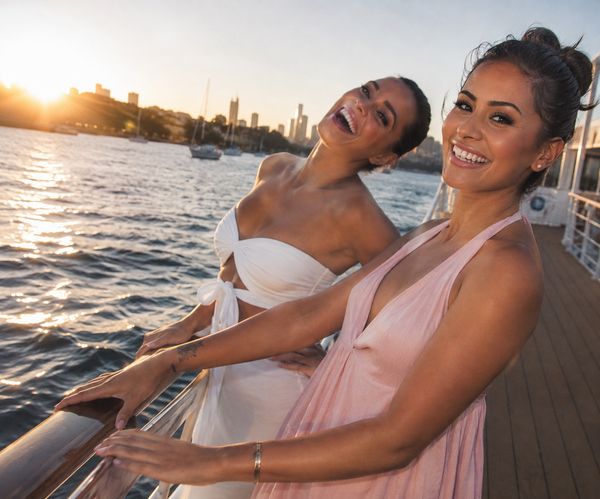 Two friends laughing on a boat deck with the city skyline behind