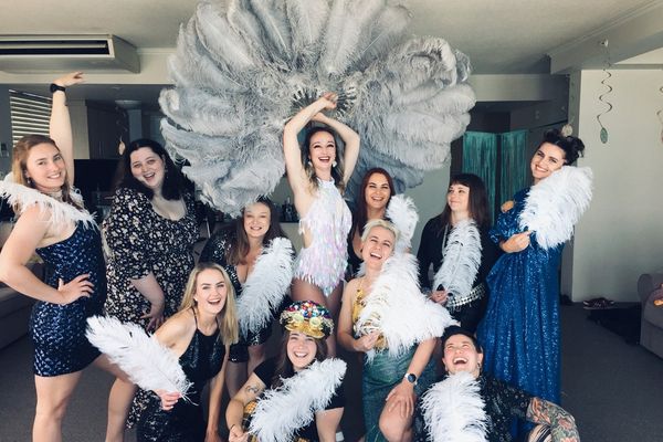 Hens group posing with white feather fans and boas during a burlesque dance class