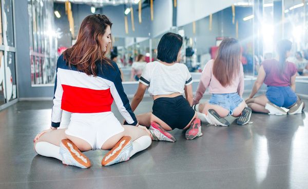 Four gorgeous ladies practise twerking while seated on the floor as part of their dance workshop in a private studio