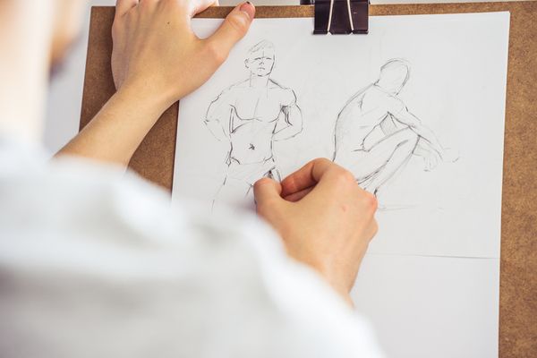 A hen sketching two male figures on paper at a life drawing class
