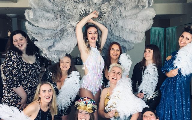A hens group posing with white feather fans at a burlesque class