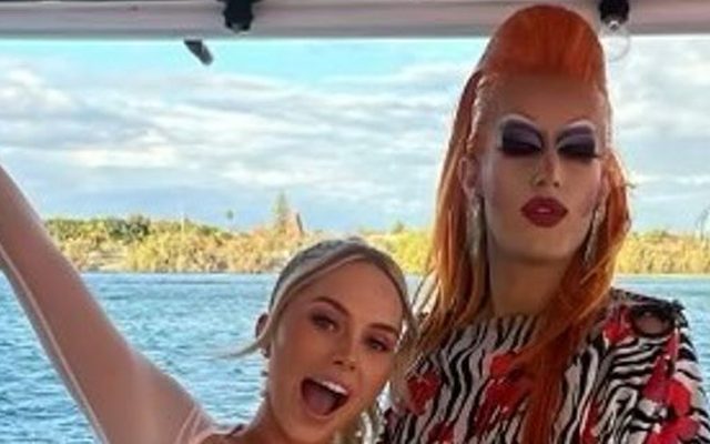 A friend waving beside a drag queen in a zebra print gown on a boat