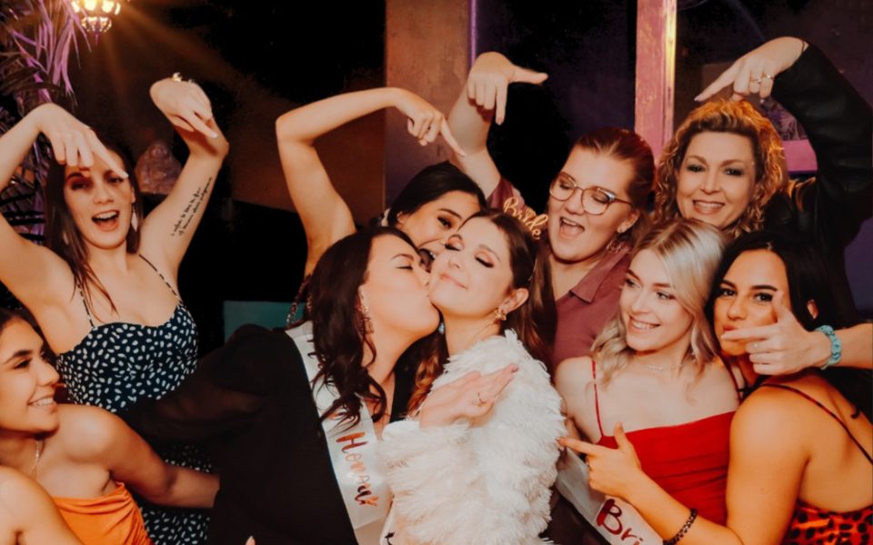 A hens group dancing around the bride in a white jacket
