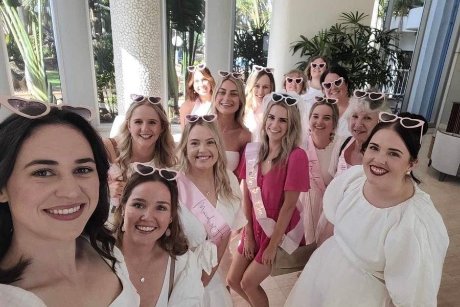 A hens group selfie in heart sunglasses and white dresses