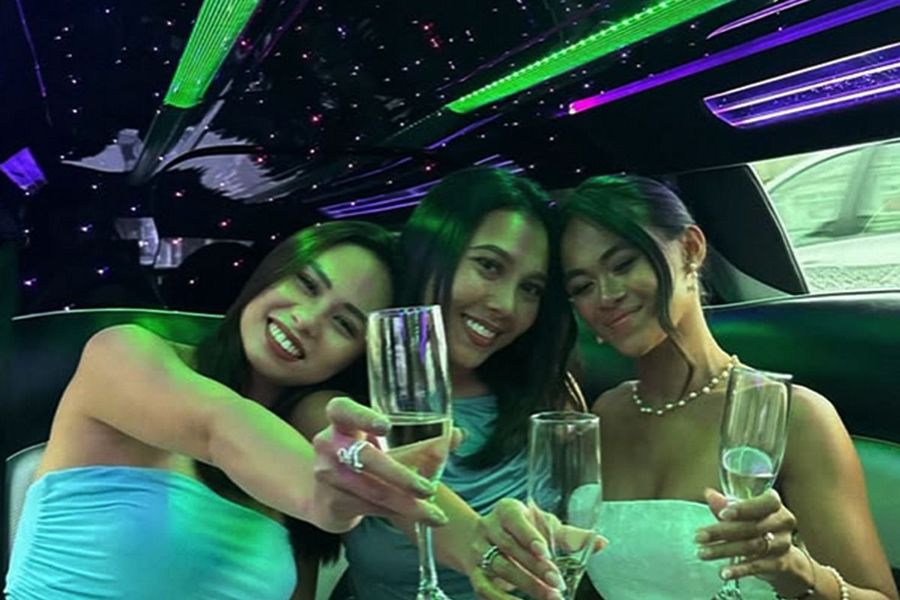 Three friends raising glasses of bubbly in a limo lit up in green