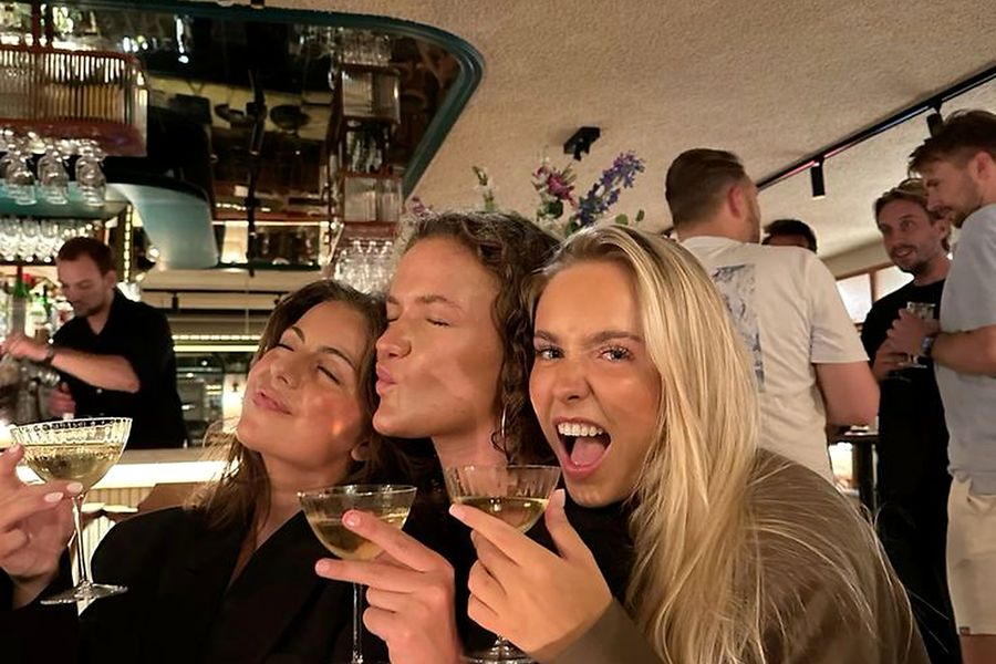 Three friends laughing with champagne at a candlelit bar