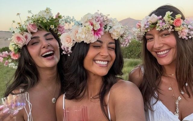 Three friends in flower crowns laughing in a selfie