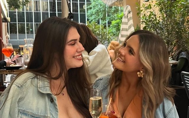 Two friends laughing over drinks on a riverside terrace in Melbourne
