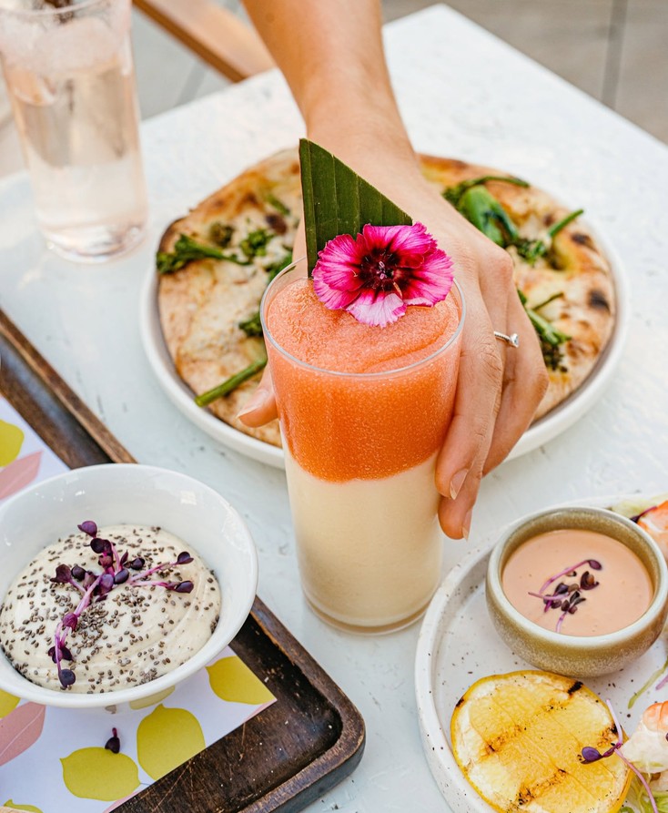 A frozen pink and cream drink topped with a bright pink flower on a brunch table