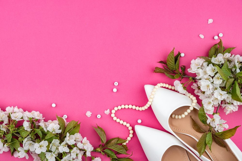 White heels, pearls and blossom on a pink background