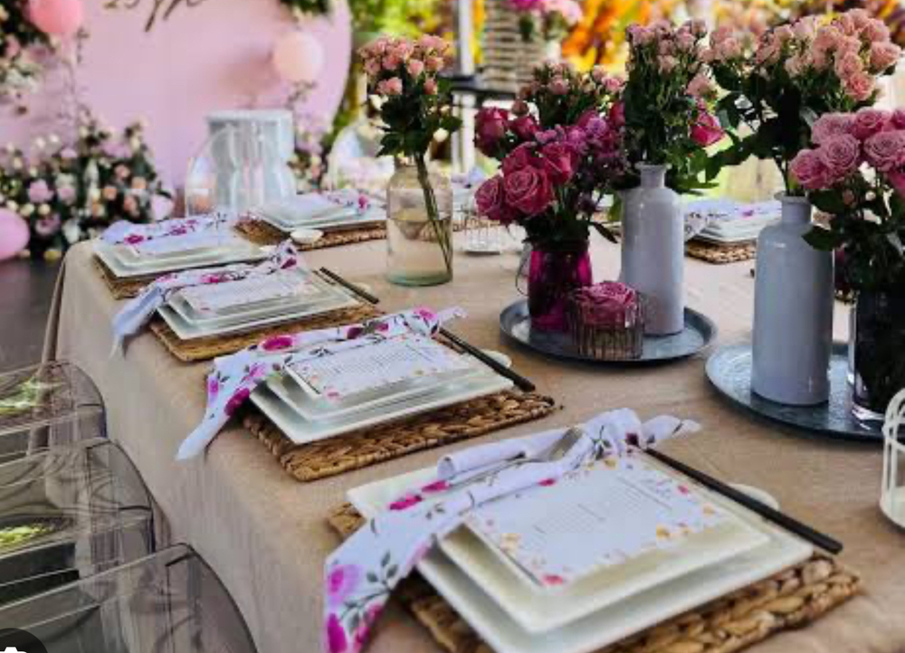 A long table set with pink flowers, candles and white plates