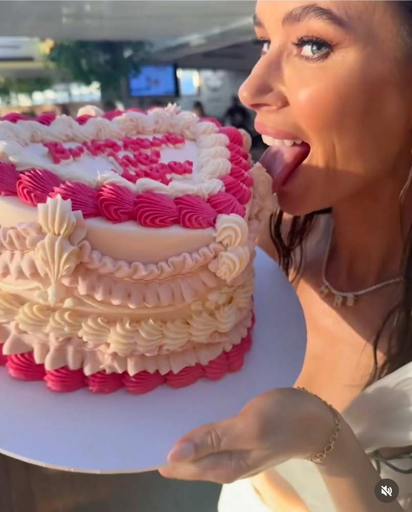 A pink and white piped cake, with Britt going in for a taste