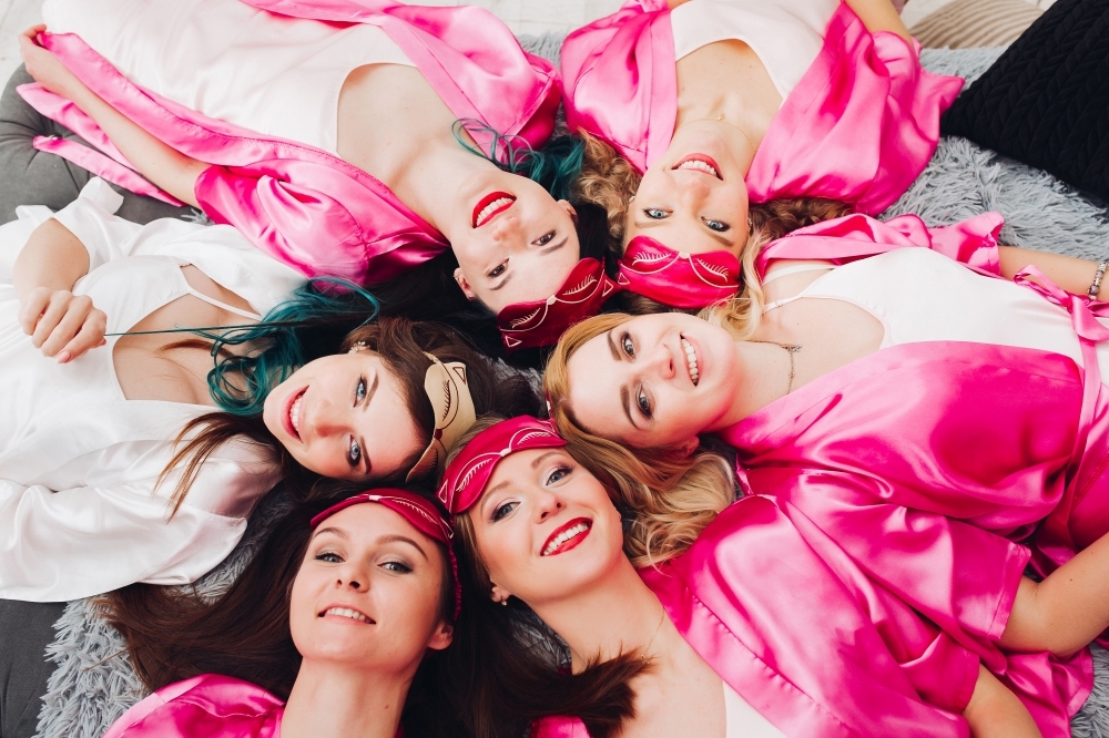 Hens in pink robes lying in a circle, heads together, shot from above