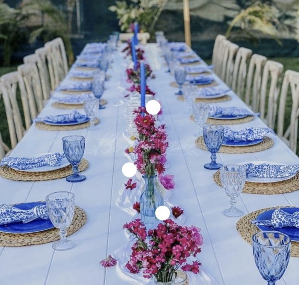 A long table set with blue and white plates, blue glassware and pink flowers